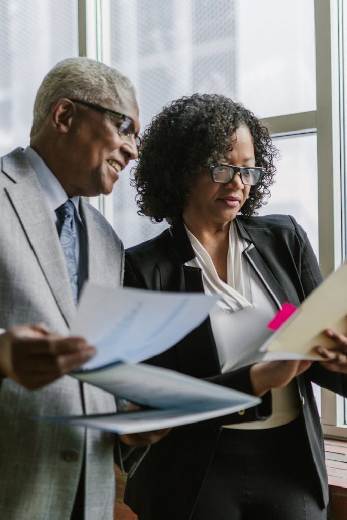 Two business professionals discussing documents with a city view in the background.